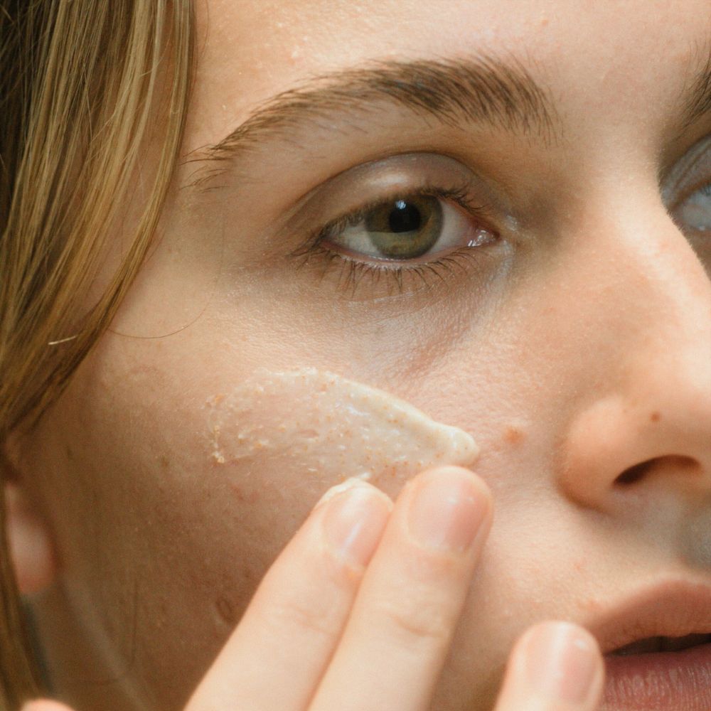 fille qui exfolie son visage avec un gomma a grain