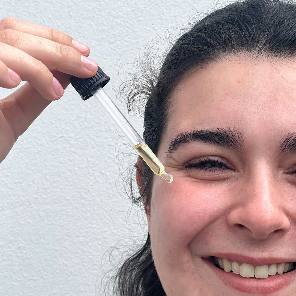 femme qui met de l'huile végétale sur son visage avec une pipette